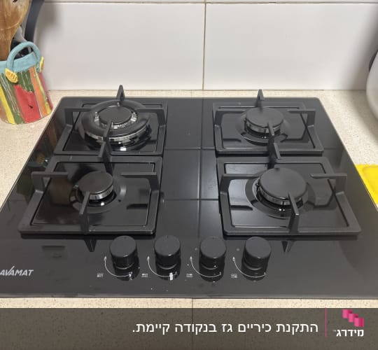 כיריים גז שחורות עם ארבעה מבערים במטבח